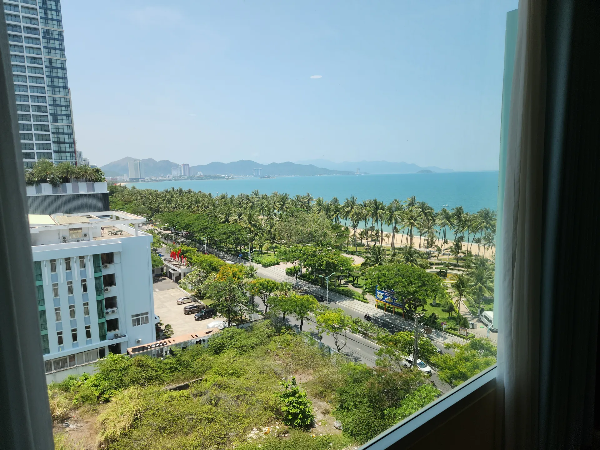 View from a hotel room at Ngoc Khanh Hotel in Nha Trang overlooking palm trees, beach, and ocean