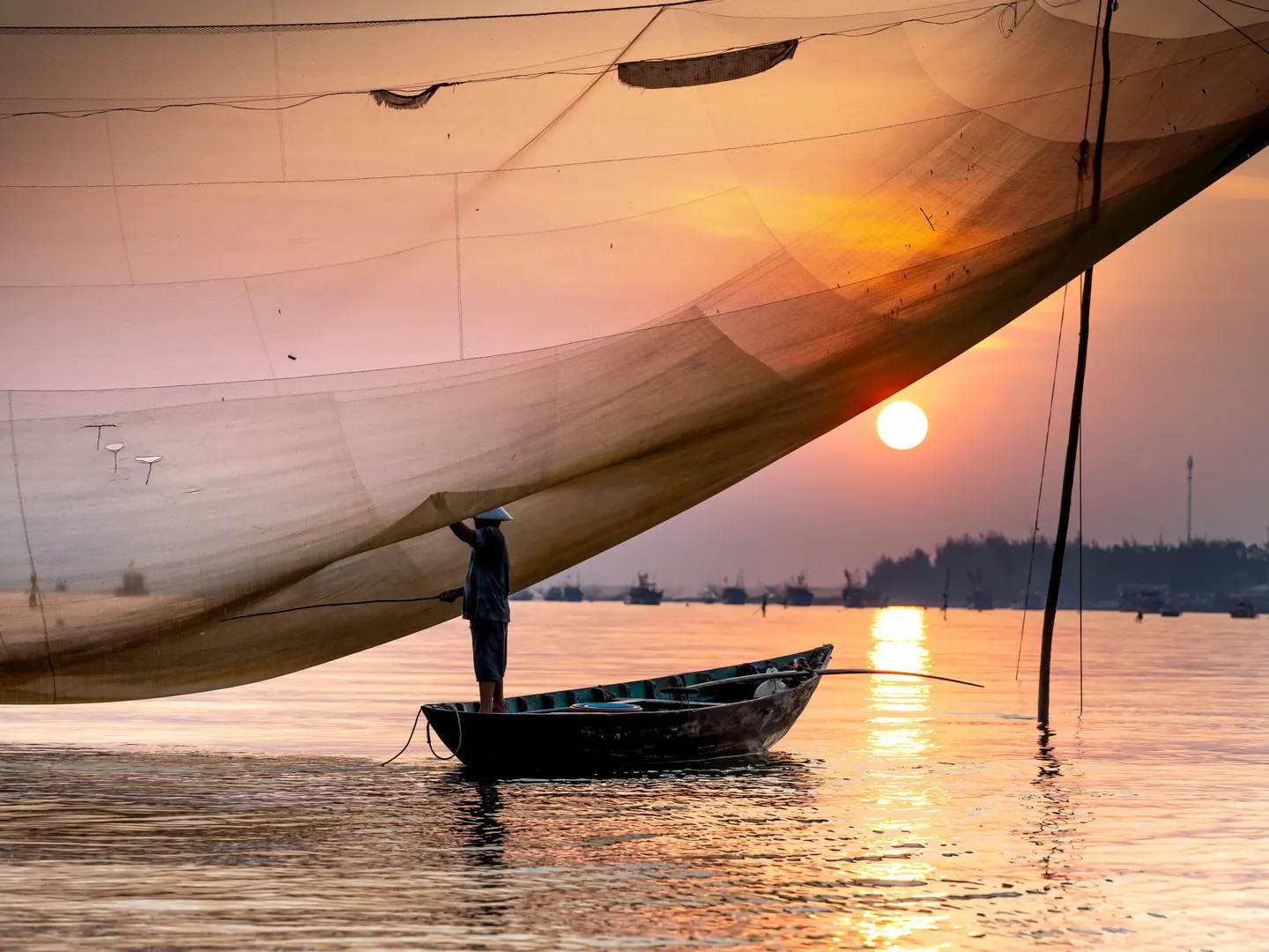  Traditional Vietnamese fishing boat with net spread for casting with a background of the setting sun in Hoi An, a popular holiday destination in Vietnam 
